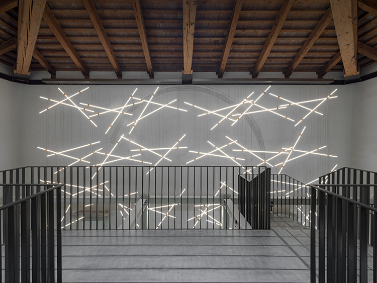 Suspended LED light lines from Barthelme in front of a wall