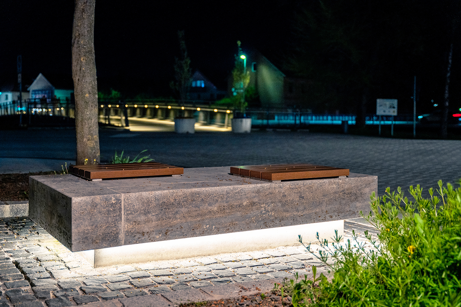 Underlit bench in front of a bridge